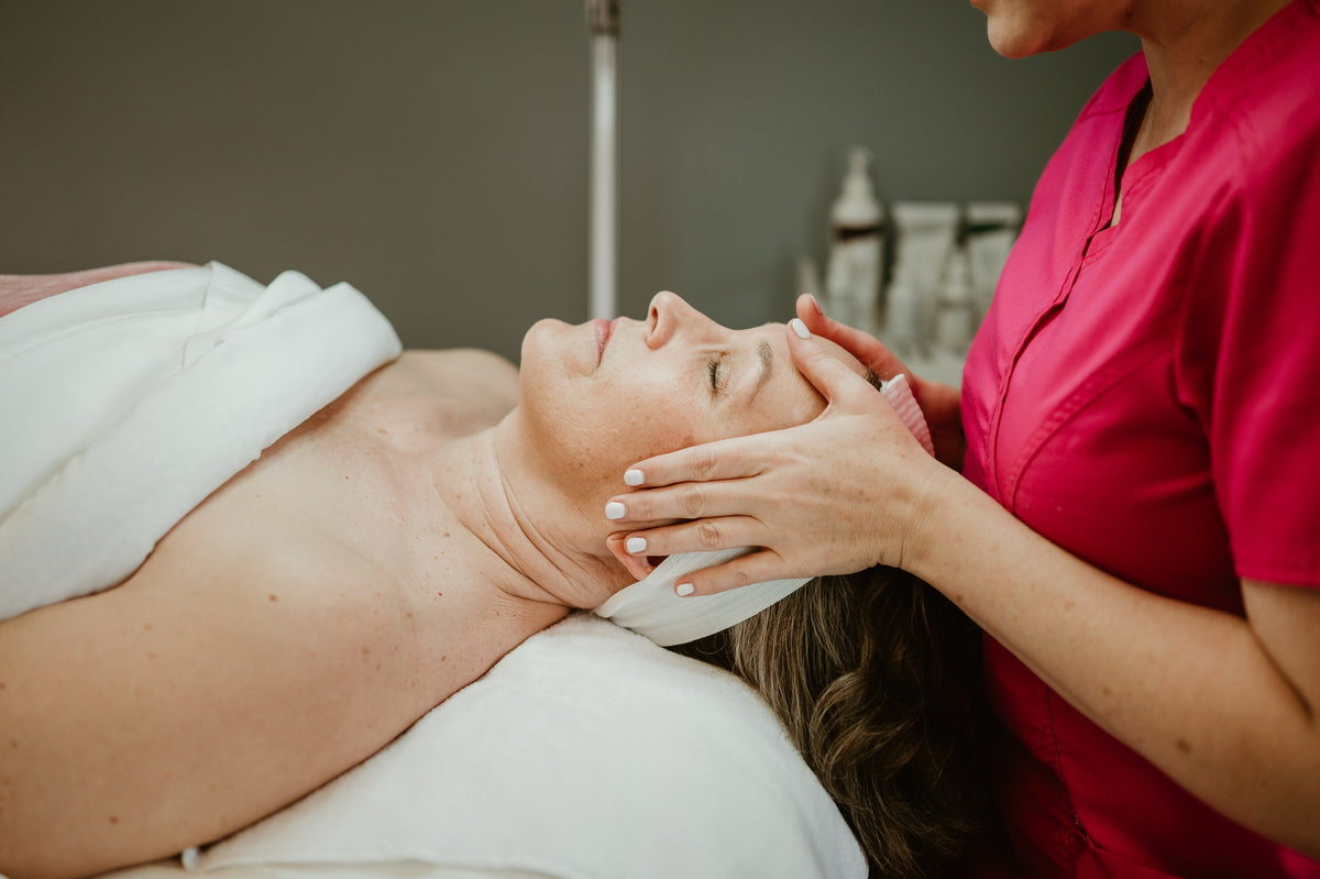 Person receiving a facial treatment from another person in a clinical setting.