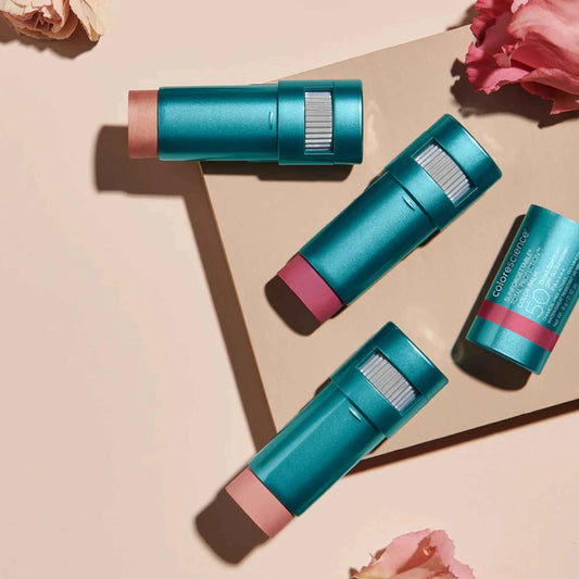 Three teal and pink lip balm sticks on a beige surface with pink flowers.
