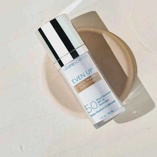 Cosmetic bottle labeled 'Even Up' with a beige powder on a light background