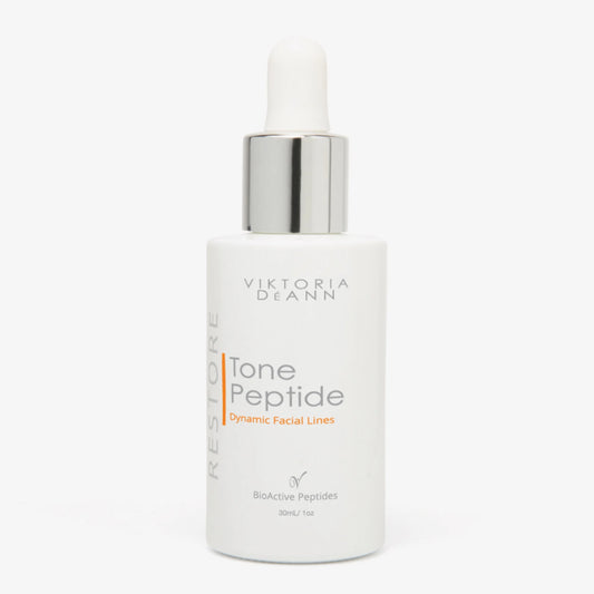 Viktoria Deann Restore Tone Peptide Dynamic Facial Lines serum in a white bottle with a silver dropper cap, on a light gray background.